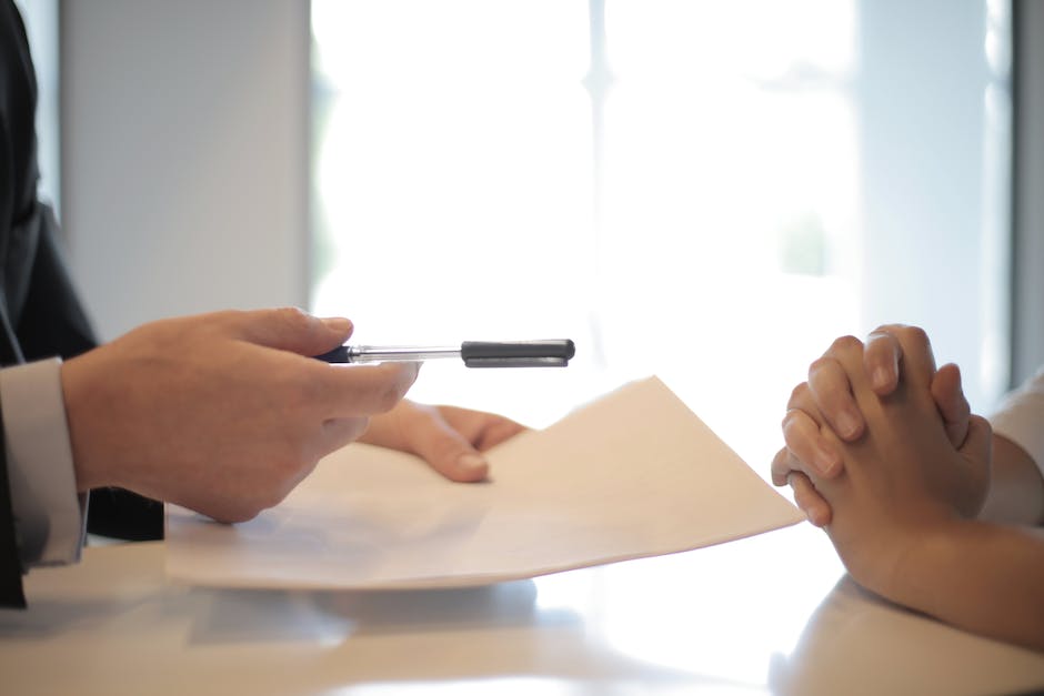 Image depicting a person signing auto loan documents
