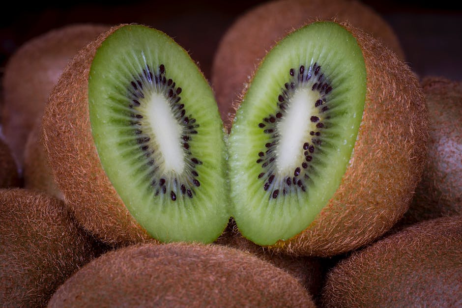 A close-up image of a kiwi fruit, with the inside exposed, showing its vibrant green color and black seeds.