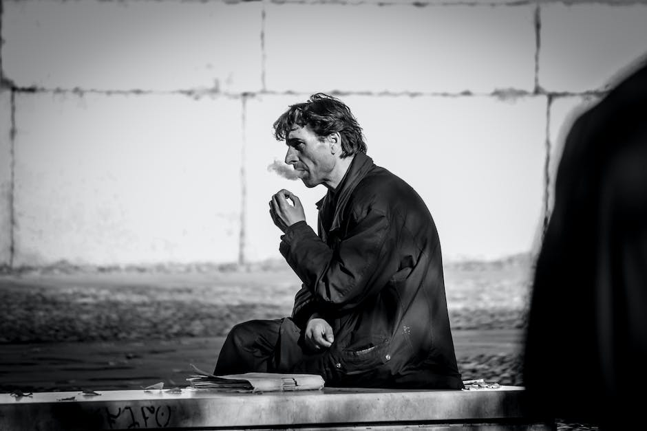 A person sitting alone on a bench, looking sad and worried.
