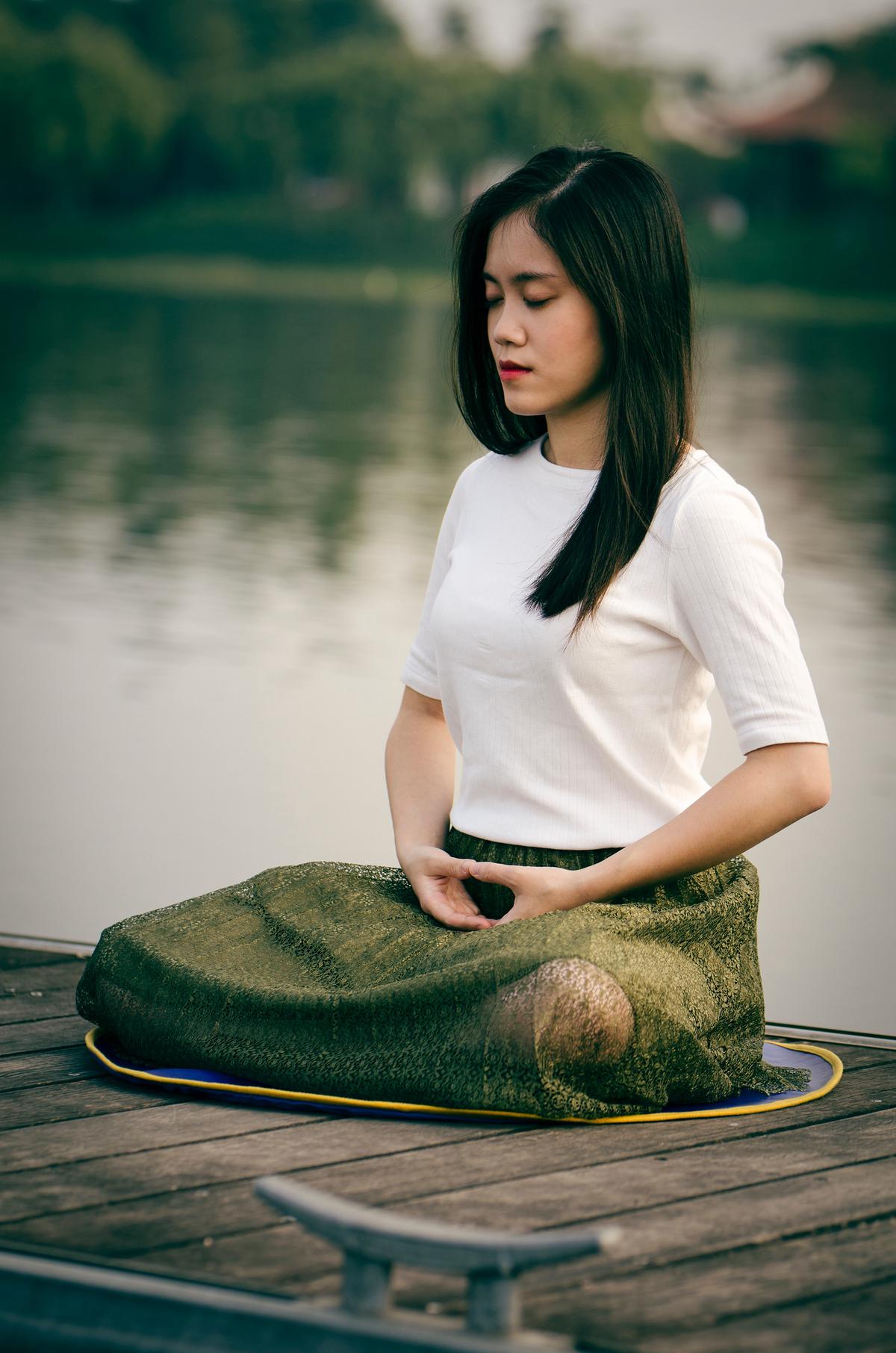 A person meditating in nature, representing stress management